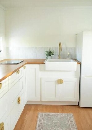 Una cucina con mobili bianchi, un piano di lavoro in legno, un lavello e un frigorifero.