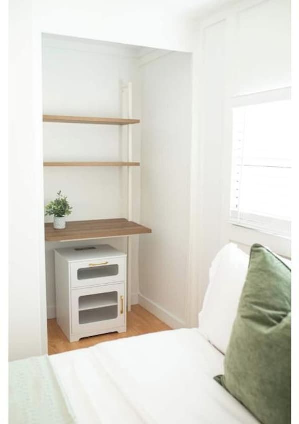 Un dormitorio con cama, mesita de noche, cómoda y ventana.