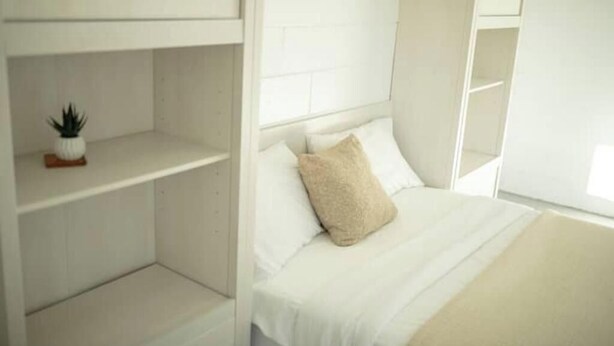 A minimalist bedroom with a bed, a shelf, and a potted plant. - -Relaxing 80 Acre Studio Space- (Groveland)