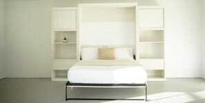 A minimalist bedroom with a bed, built-in shelving, and a neutral color scheme.
