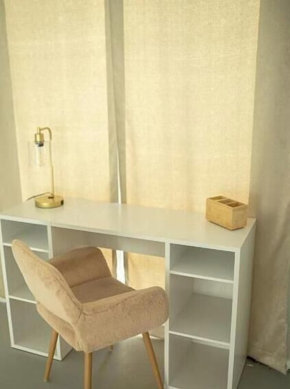 A white desk with a chair, a lamp, and a wooden box.