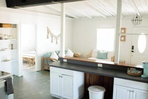 Een ruime keuken met witte kasten, een zwart aanrecht en een eethoek met een houten vloer.