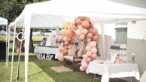 A tent with a white tablecloth, balloons, and a 'BABY' sign.