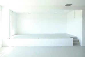 Une pièce minimaliste dotée d’une grande fenêtre, d’une banquette intégrée et d’un escalier menant à un niveau supérieur.