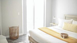 A bedroom with a bed, a bedside table, a lamp, and a wicker basket.