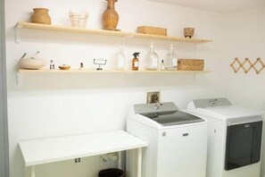 A laundry area with two white washing machines, shelves with baskets and bottles, and a white countertop. - -Private Home on 50 acres - Cows & Pool Access- (Groveland)