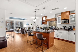 Una cocina moderna con una isla central, taburetes de bar y un comedor con vistas.