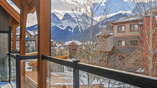 A balcony with a view of snow-covered mountains and buildings.