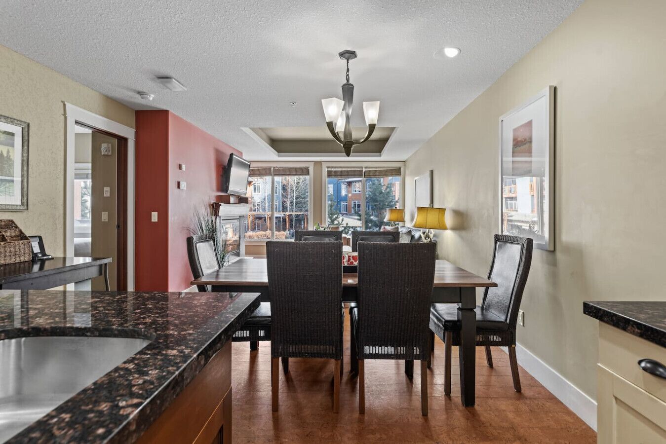 A dining area with a central table, chairs, and a chandelier.