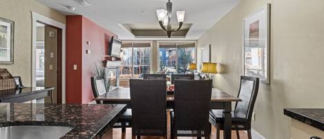 A dining area with a central table, chairs, and a chandelier.