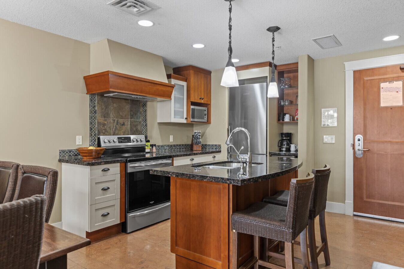 A modern kitchen with a central island, stainless steel appliances, and a wooden cabinet.