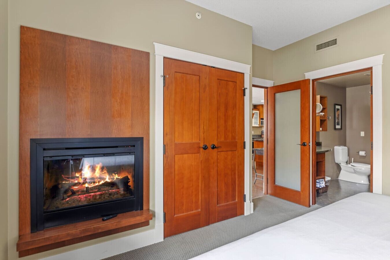 Une chambre d’hôtel avec une cheminée, une armoire en bois et une salle de bain visible à travers une porte ouverte.