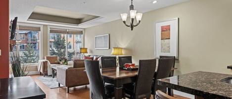 A modern dining area with a wooden table, chairs, and a chandelier.