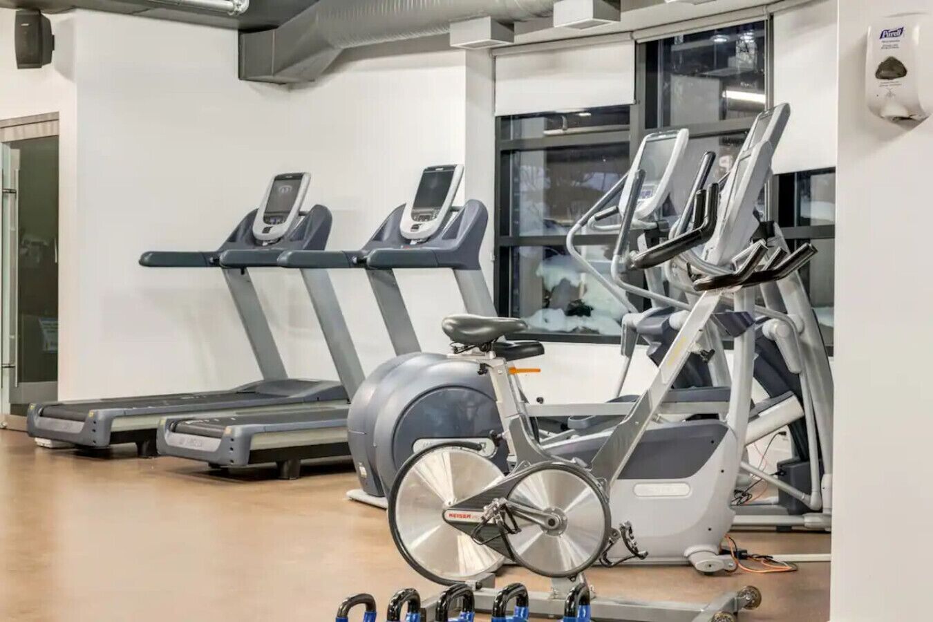 A gym with treadmills, an elliptical, and dumbbells.