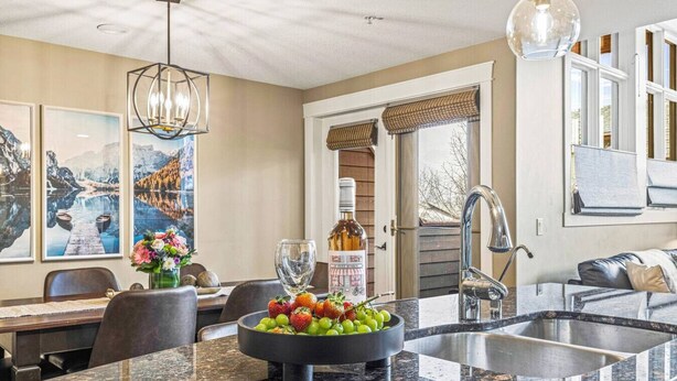 A modern kitchen with a granite countertop, a bowl of fruit, and a wine bottle.