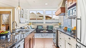 A modern kitchen with a central island, a dining area with a sofa, and a view of the neighborhood.