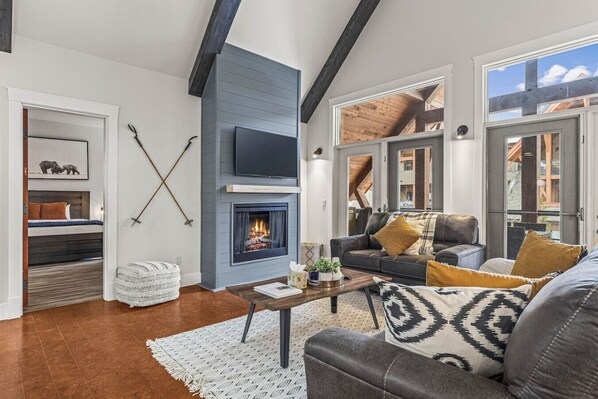 A modern living room with a fireplace, a sofa set, and a coffee table. - Mountain View Penthouse with Pool & Hot Tub (Canmore)