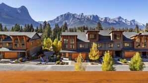 A row of log cabin-style buildings with large windows and a mountain backdrop. - Serenity Awaits | Mountain Views (Canmore)