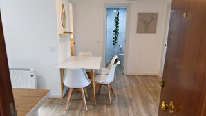 Eine moderne Küche mit weißen Schränken und einer Holzarbeitsplatte. Es gibt einen Essbereich mit einem weißen Tisch und Stühlen.
