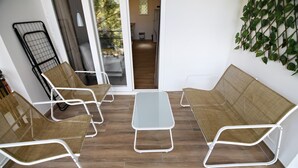 Ein modernes Zimmer mit einer Schiebeglasdoor zum Balkon, möbliert mit Korbstühlen und einem kleinen Tisch.