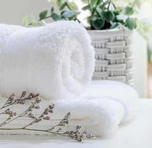 A rolled white towel, a woven basket, and dried lavender flowers.