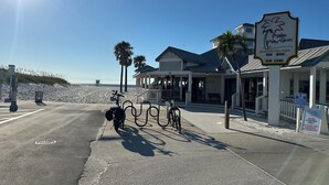 Een gebouw aan het strand met een bordje voor Palm Pavilion, een grillrestaurant en bar aan het strand, en een aangewezen parkeerplaats.
