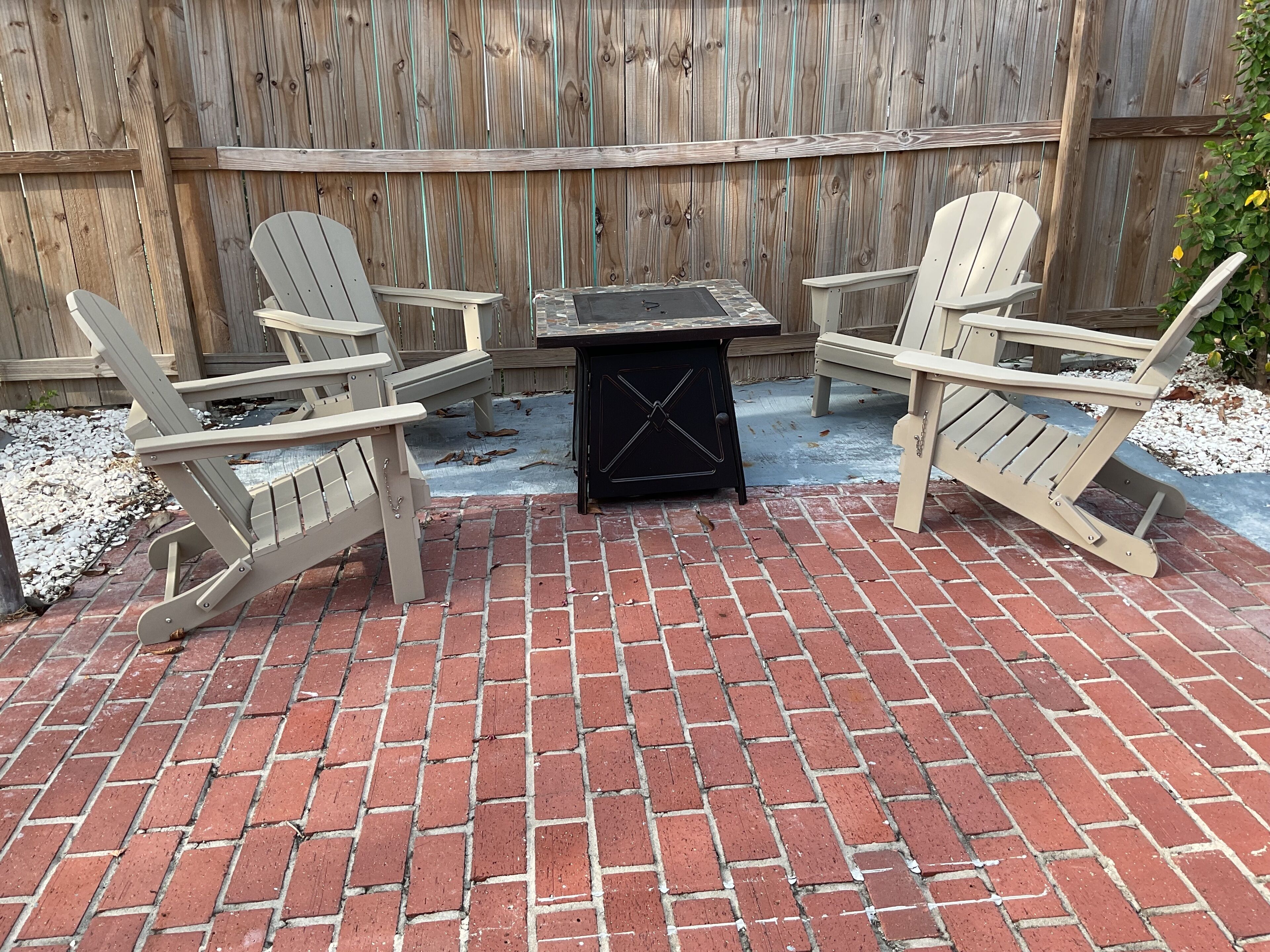 A patio with two Adirondack chairs and a small table.