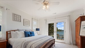 A bedroom with a bed, a nightstand, a dresser, and a sliding glass door leading to a balcony.