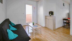 Un ambiente compatto con un divano nero, un tavolino, un mobile e una sedia.