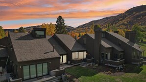 A modern house with a spacious patio area, large windows, and a view of the surrounding hills. - 2BR Walk to Ski - Spa-like Bath (Park City)
