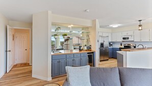 A modern kitchen with grey cabinets, a central island, and a dining area. - Lake & Hill Country Views, 2 Master Suites, Pet Friendly, Deck w/ Grill (Canyon Lake)