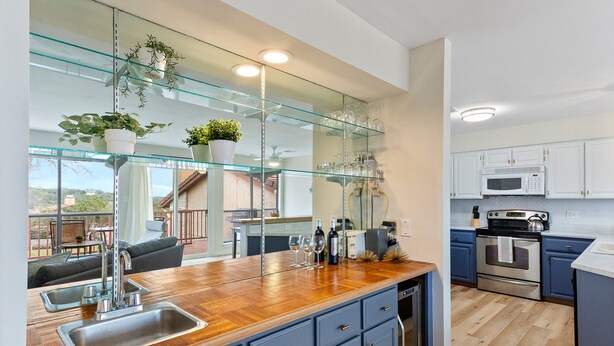 A modern kitchen with a wooden countertop, stainless steel sink, and a glass backsplash. - Lake & Hill Country Views, 2 Master Suites, Pet Friendly, Deck w/ Grill (Canyon Lake)