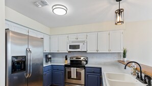 A modern kitchen with stainless steel appliances, blue cabinets, and a double sink. - Lake & Hill Country Views, 2 Master Suites, Pet Friendly, Deck w/ Grill (Canyon Lake)