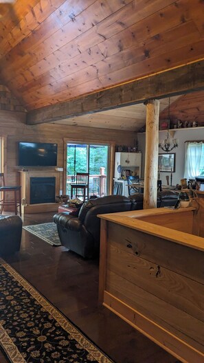 Ein gemütliches Blockhausschlafzimmer mit Kamin, Ledersofa, Holzesstisch und Fernseher.