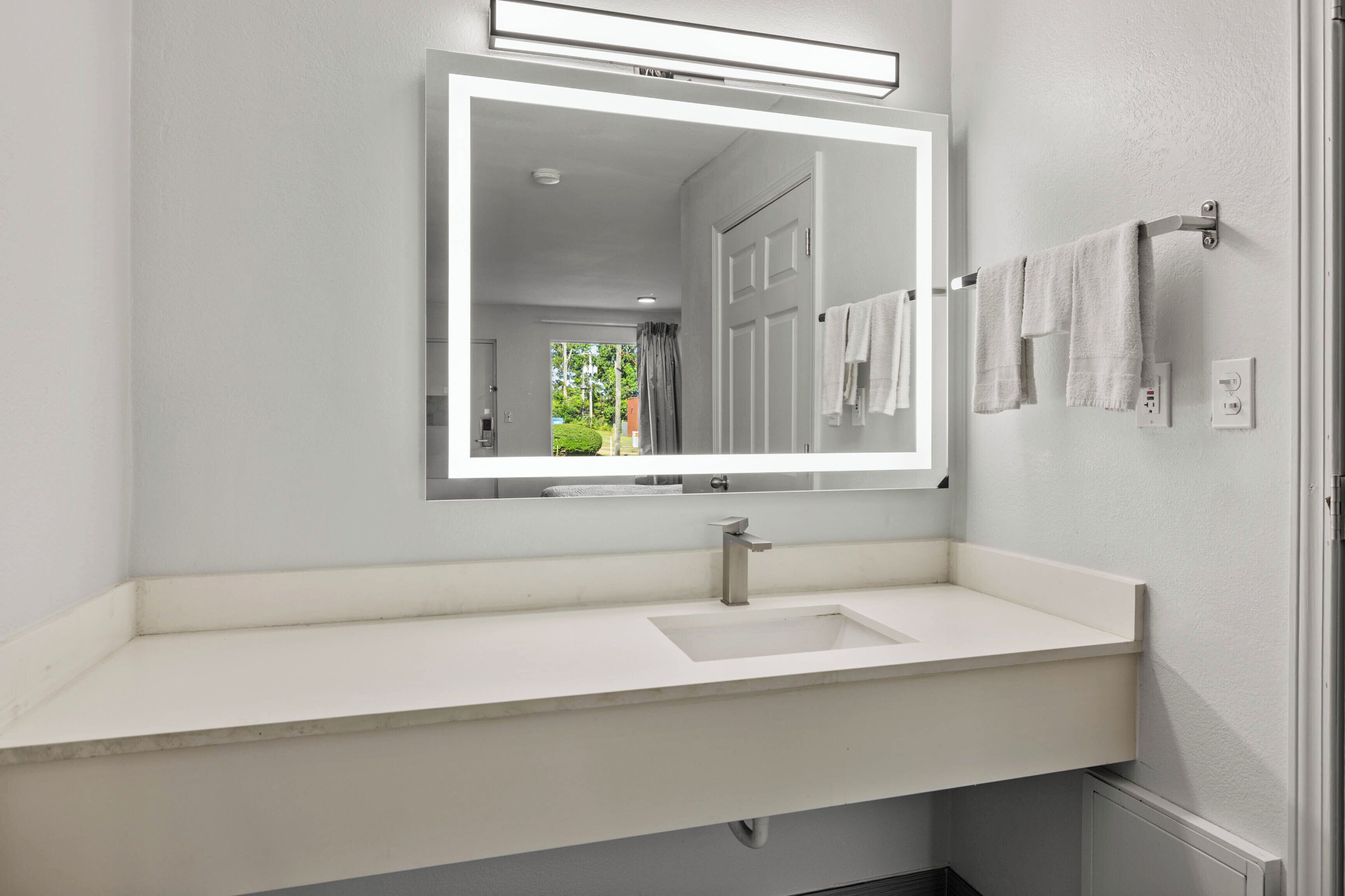 Ein modernes Badezimmer mit Waschbecken, Spiegel und Handtuchhalter.