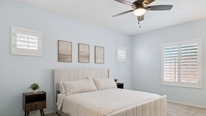 A bedroom with a bed, a nightstand, a ceiling fan, and a window with blinds. - Verrado Views Retreat - Sleeps 12 + Pool (Buckeye)