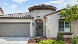 A residential house with a garage, a front door, a small porch, and a landscaped garden. - Verrado Views Retreat - Sleeps 12 + Pool (Buckeye)