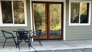 A house with a front door, two windows, and a patio with a table and chairs. - Hotel-Style Retreat on private property - Sleeps 4 (Three Rivers)