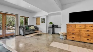 A modern living room with a grey sofa, a coffee table, and a wooden dresser with drawers. - Hotel-Style Retreat on private property - Sleeps 4 (Three Rivers)