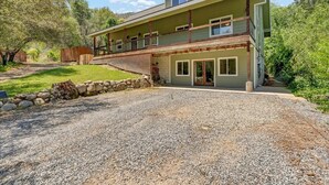 A two-story house with a covered porch and a gravel driveway. - Hotel-Style Retreat on private property - Sleeps 4 (Three Rivers)