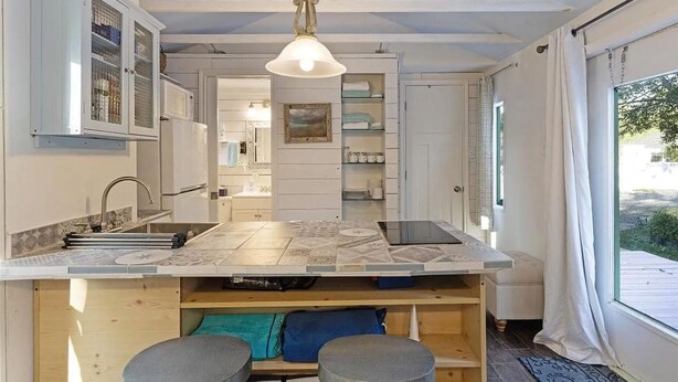A compact kitchen with a central island, built-in cabinets, and a hanging light fixture. - Tiny house 5 minutes near Kemah boardwalk! (Bacliff)