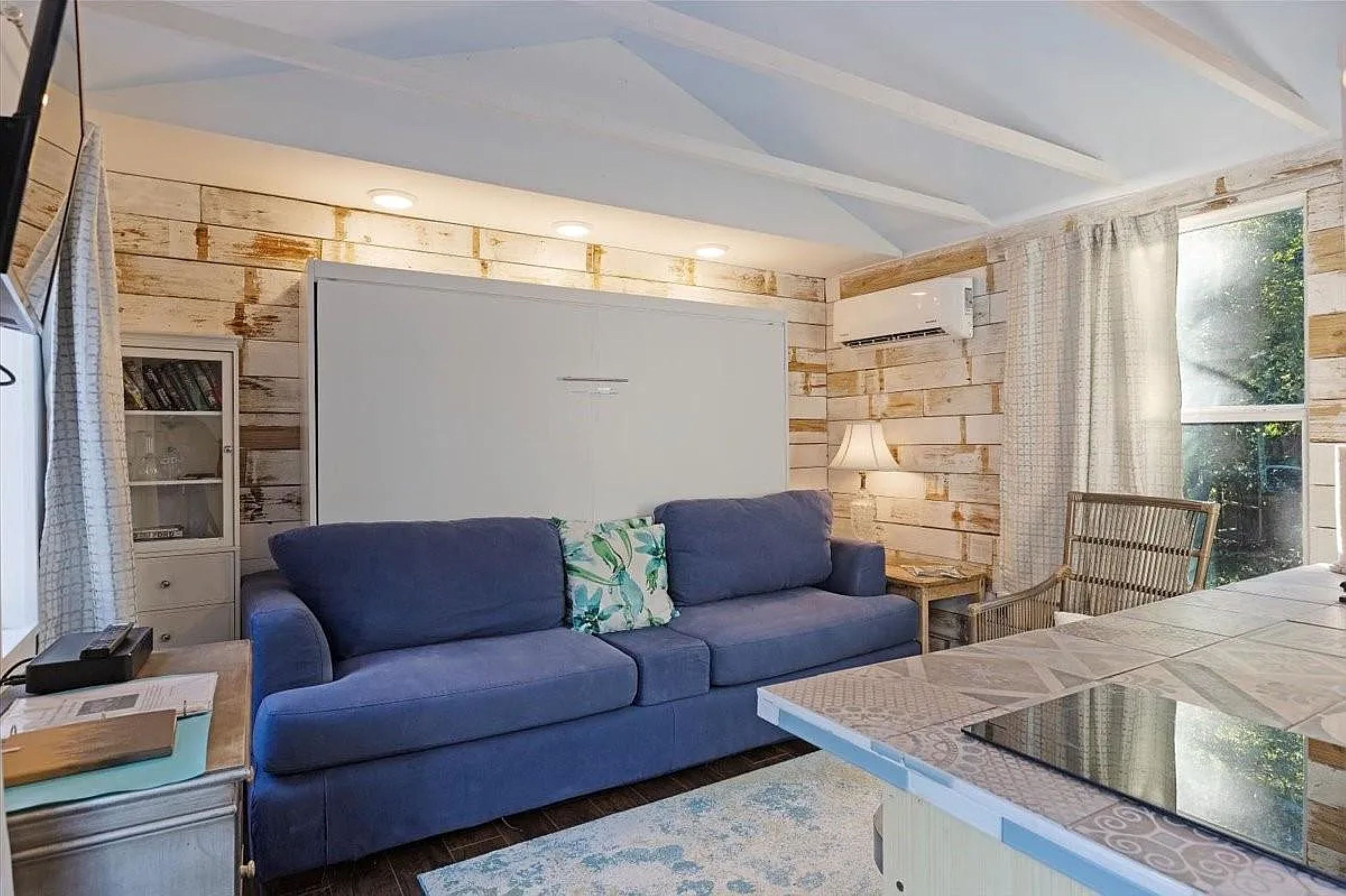 A modern living room with a sofa, a glass coffee table, and a bookshelf.