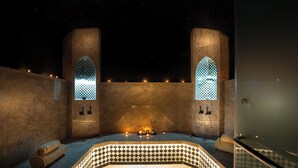 A spa room with a checkered floor, two arched windows, a bathtub, and a massage table. - Villa Harmonie Luxe & Bien-être in the golf residence with spa (Marrakech)