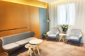 A modern hotel room with a sofa, two armchairs, a small round table, and a floor lamp. - Meihe Meijia Collection Hotel (Jiaozhou Bus Terminal) (Jiaozhou)