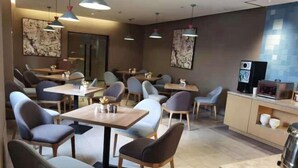 A restaurant with multiple tables and chairs, a counter with a coffee machine, and artwork on the walls.