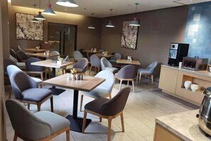 A restaurant with multiple tables and chairs, a counter with a coffee machine, and artwork on the walls. - Meihe Meijia Collection Hotel (Jiaozhou Bus Terminal) (Jiaozhou)