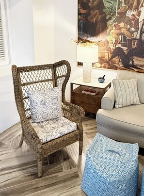 A wicker chair with a patterned cushion, a small table with a lamp, a bowl, and a couch with a pillow. - The Sunny Patio Oasis (San Juan)