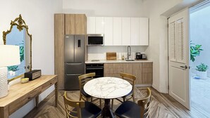 Una cocina compacta con comedor, que incluye una mesa de mármol, sillas de madera y un refrigerador moderno.