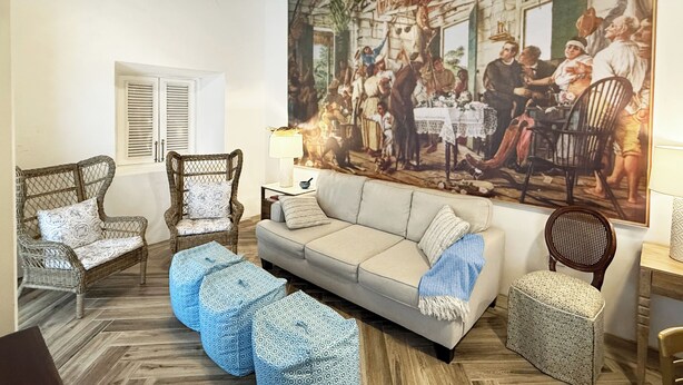 Una sala de estar con un sofá, dos sillones, una mesa de centro y un cuadro grande en la pared.