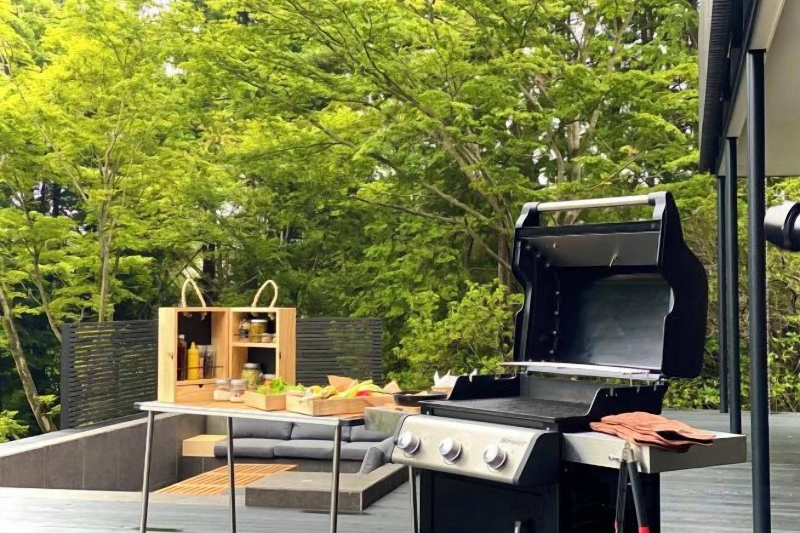 Ett utomhusområde med grillplats, sittplatser och ett bord med mat och dryck.
